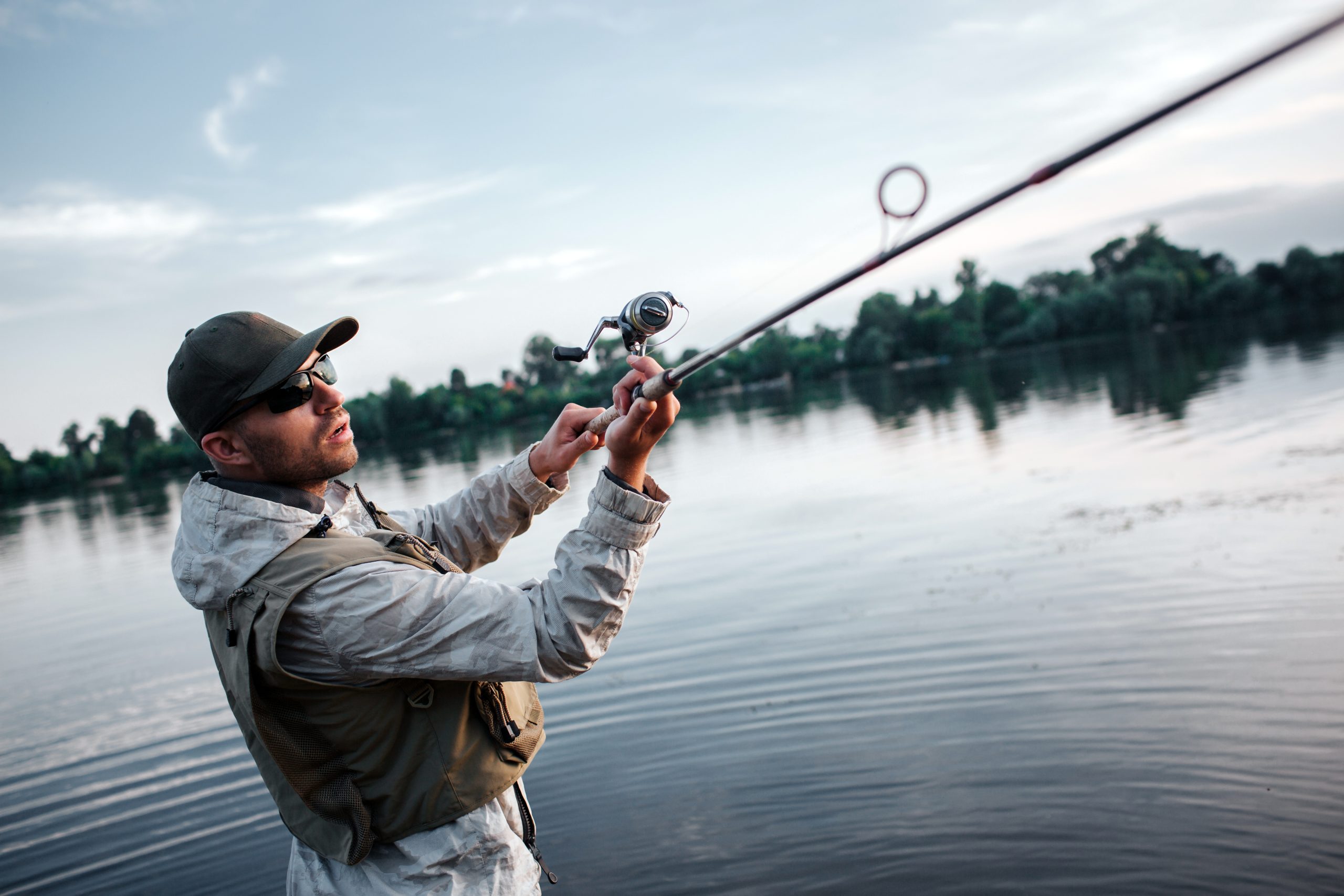 Angler casting a fly rod on a river at dawn